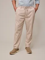 Pantalón de vestir color beige, de corte recto, con bolsillos laterales y traseros. Se ajusta a la cintura con cordón.
