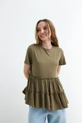 Remera de algodón color verde militar con cuello redondo, mangas cortas y detalle de volados fruncidos en la parte inferior.