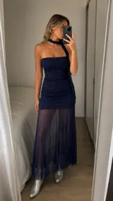 Vestido largo azul marino con diseño strapless y detalle de cuello halter. Presenta un cuerpo ajustado con frunces laterales y una falda inferior transparente de tul que aporta movimiento y elegancia.