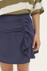 Falda corta azul marino con detalle de volado drapeado en el lateral y cierre.