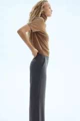 Pantalón de vestir color gris oscuro con corte bootcut. Presenta pretina prolongada con cierre oculto, bolsillos laterales al bies y bolsillos traseros ribeteados. Diseño con raya marcada adelante y atrás.