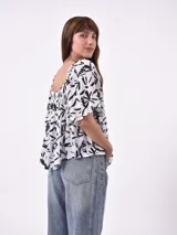 Blusa negra con escote cuadrado, fruncido en el busto y mangas cortas amplias.