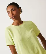 Blusa blanca de poliéster con cuello redondo, mangas cortas, cierre trasero en forma de gota, pequeñas aberturas laterales y acabados en pespuntes en las mangas y el cuello.