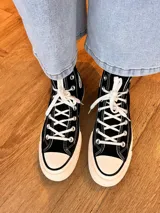 Zapatillas de lona color beige, tipo bota, con cordones marrones, puntera de goma y logo de peach engomado.