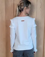 Remera de algodón de manga larga, color blanco, con detalle de volados en los hombros y en los puños.