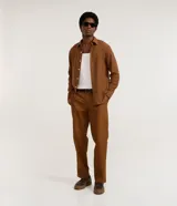 Pantalón de sarga color marrón, de corte recto, con trabillas para cinturón, cierre tradicional y bolsillos laterales y traseros.