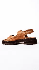 Sandalias de mujer con plataforma gruesa y dentada de color negro. La capellada presenta un estampado de piel de serpiente en tonos beige y marrón, con dos tiras ajustables con hebillas de cuero marrón.