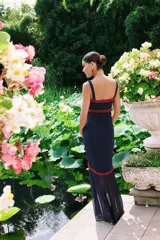 Vestido largo azul marino de Lady Pipa, con tirantes anchos, escote corazón con detalles bordados en rojo y parte inferior translúcida con tajo frontal y ribete rojo.