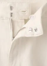 Pantalón jeans estilo balloon de tiro medio y largo tobillero, confeccionado en 100% algodón. Presenta detalle de pinzas en la cintura, dos bolsillos laterales, cierre de gancho y cremallera, y puños elásticos en los tobillos.