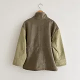 Chaqueta de silueta relajada, confeccionada en paño de lana color verde militar con detalles en pana de algodón marrón en el cuello y los bolsillos. Cuenta con cuello alto, bolsillos frontales amplios y cordón regulable en la cintura.