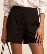 Short de sastrería negro, tiro alto, con cierre frontal de botones visibles.