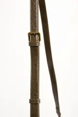 Cartera tipo shopper color marrón, con solapa frontal decorativa en tono más oscuro y tiras con nudos. Incluye herrajes dorados y un charm colgante con cuentas de madera.