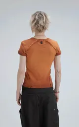 Remera de manga corta y cuello redondo, confeccionada en tejido ribb 100% algodón, de calce ajustado al cuerpo y largo a la cadera. El color es un marrón oscuro con efecto desgastado o teñido. Presenta costuras externas visibles en los hombros y laterales.