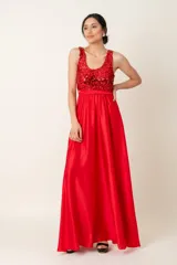 Vestido largo rojo con cuerpo de lentejuelas y falda de satén con caída fluida. Presenta escote redondo, sin mangas y un lazo en la cintura.