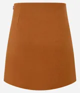 Minifalda marrón de polivelour con cierre lateral, solapas con hebillas y pliegues.