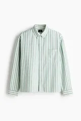 Camisa de manga larga de algodón Oxford con patrón de rayas verticales en color verde y blanco, cuello americano, cierre frontal de botones y un bolsillo aplicado en el pecho.