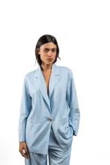 Blazer de lino color celeste, con solapas clásicas, cierre frontal de un botón y bolsillos laterales.
