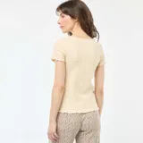 Camiseta color beige de punto canalé, con cuello redondo y mangas cortas con volados.