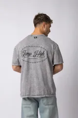 Remera de algodón con efecto lavado ácido en color gris, de corte holgado y manga corta. Presenta estampados gráficos minimalistas en el pecho y cuello redondo acanalado.