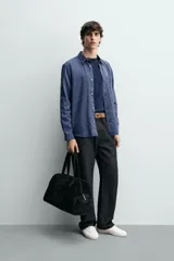 Camisa de corte regular fit en color azul, confeccionada en mezcla de lyocell y algodón, con cuello camisero, manga larga con puños abotonados, cierre frontal con botones y un bolsillo aplicado en el pecho.