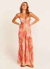 Vestido largo de tirantes finos con estampado de hojas en tonos coral, naranja, verde y amarillo. Presenta escote en V con detalle de nudo y aberturas en los laterales de la cintura.