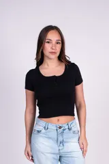 Remera entallada de manga corta negra, con escote redondo y detalle de tres botones frontales.