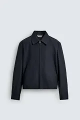 Cazadora cropped fit color azul marino, confeccionada en tejido de algodón. Presenta cuello solapa, manga larga con puño abotonado, bolsillos frontales de vivo y un bolsillo interior. El cierre es frontal con cremallera.