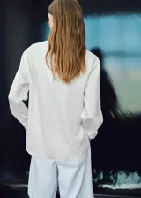 Blusa de manga larga con diseño de rayas verticales, cuello redondo y pañuelo integrado al tono. Presenta un corte recto y cierre de botón en la parte posterior.