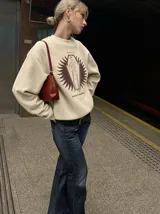 Buzo de cuello redondo color tostado, con estampa frontal de un esqueleto dentro de un ataúd rodeado por un diseño solar y la inscripción 'Wake Up' junto a 'Kaboa Industries'.