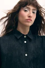 Vestido camisero negro con sobrefalda integrada, botones de nácar y estampado con leve rugosidad.