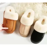 Pantuflas de gamuza color beige con plataforma y forro interior de corderito sintético. Presentan un diseño sin talón con el nombre de la marca bordado en el lateral.