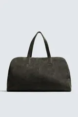 Bolso de viaje de gran tamaño confeccionado en piel con acabado de serraje. Cuenta con un compartimento principal con cierre de cremallera e imanes, interior con bolsillo con cierre y bolsillo plano, y dos asas de mano de piel.