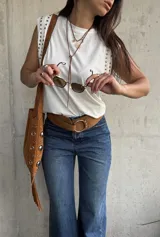 Remera sin mangas de algodón blanco, con cuello redondo y detalle de tachas metálicas en los hombros.