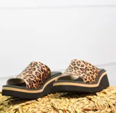 Zuecos de cuero con estampado animal print tipo leopardo, plataforma alta negra con detalle de línea beige.