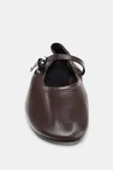 Zapato tipo bailarina de piel color marrón con efecto soft, tira delantera con hebilla metálica, suela plana y acabado en punta redonda.