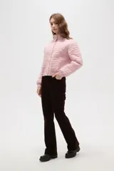 Campera corta de cuello alto, con cierre frontal de botones a presión y puños elásticos. Presenta un diseño acolchado con un patrón floral grabado en toda la superficie.