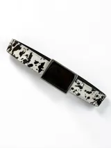 Cinturón de cuero con estampado animal print tipo vaca y hebilla rectangular de guampa natural con borde metálico.