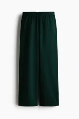 Pantalón tipo jogger de corte holgado y piernas amplias, confeccionado en felpa con interior cepillado. Presenta cintura elástica con cordón de ajuste y bolsillos laterales discretos.