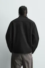 Sobrecamisa de corte regular confeccionada en tejido con estructura diagonal repelente al agua. Presenta cuello solapa, cierre frontal con botones, mangas largas con puños abotonados y bolsillos plastrón con solapa en el pecho.