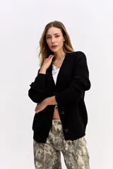 Saco de punto color crema con escote en V, cierre frontal con botones y bolsillos delanteros. Presenta un diseño de calce relajado con estructura marcada.