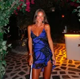 Vestido corto de microtul con estampado de mariposas azules y negras sobre fondo negro. Tiene breteles finos, escote en V con volados y falda con volados y abertura lateral.