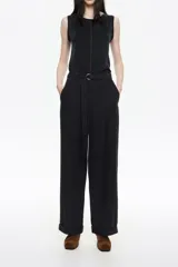 Pantalón negro de tiro alto con corte ancho y acampanado, confeccionado en tejido de viscosa y poliéster. Incluye cinturón de tela a juego con hebilla metálica en forma de "C" y puños doblados en los tobillos.