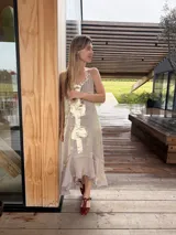 Vestido midi lila con acabado brillante y tirantes finos regulables, diseño con aplicaciones de cuero dorado en el centro y bajo asimétrico con volados.