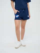 Bermuda deportiva azul marino Umbro del Club Nacional de Football, con bolsillos laterales, cordón ajustable en la cintura y detalles con líneas laterales. Incluye el escudo del club y el logo de la marca bordados.
