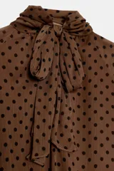 Blusa de cuello subido con diseño de lunares, manga larga abullonada con puños elásticos y forro interior.