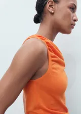 Top sin mangas de tejido de punto fino, color naranja, con cuello drapeado y bajo asimétrico. Presenta un diseño entallado con tirantes anchos.