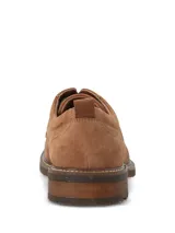 Zapato de vestir tipo derby marca Hush Puppies, confeccionado en cuero gamuzado color tostado. Presenta cordones oscuros, costuras reforzadas y suela de goma con efecto moteado.
