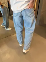 Jean de corte barrel y silueta oversize, en tono azul claro con efecto lavado. Presenta un diseño de tiro medio y pernera amplia que se estrecha ligeramente hacia el tobillo.