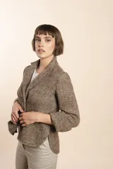 Chaqueta marrón de lana con cuello, solapa y bolsillos ojal. Forro solo en las mangas y terminaciones envivadas. Esquinas redondeadas y mangas con corte en puño que permiten transformarla en manga 3/4. Más larga en la espalda que en la delantera. Abrochadura con dos botones.