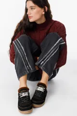 Zuecos de cuero negro con diseño tipo sneaker, cordones y suela de goma color caramelo. Presentan detalle de marca Petra en la lengüeta.